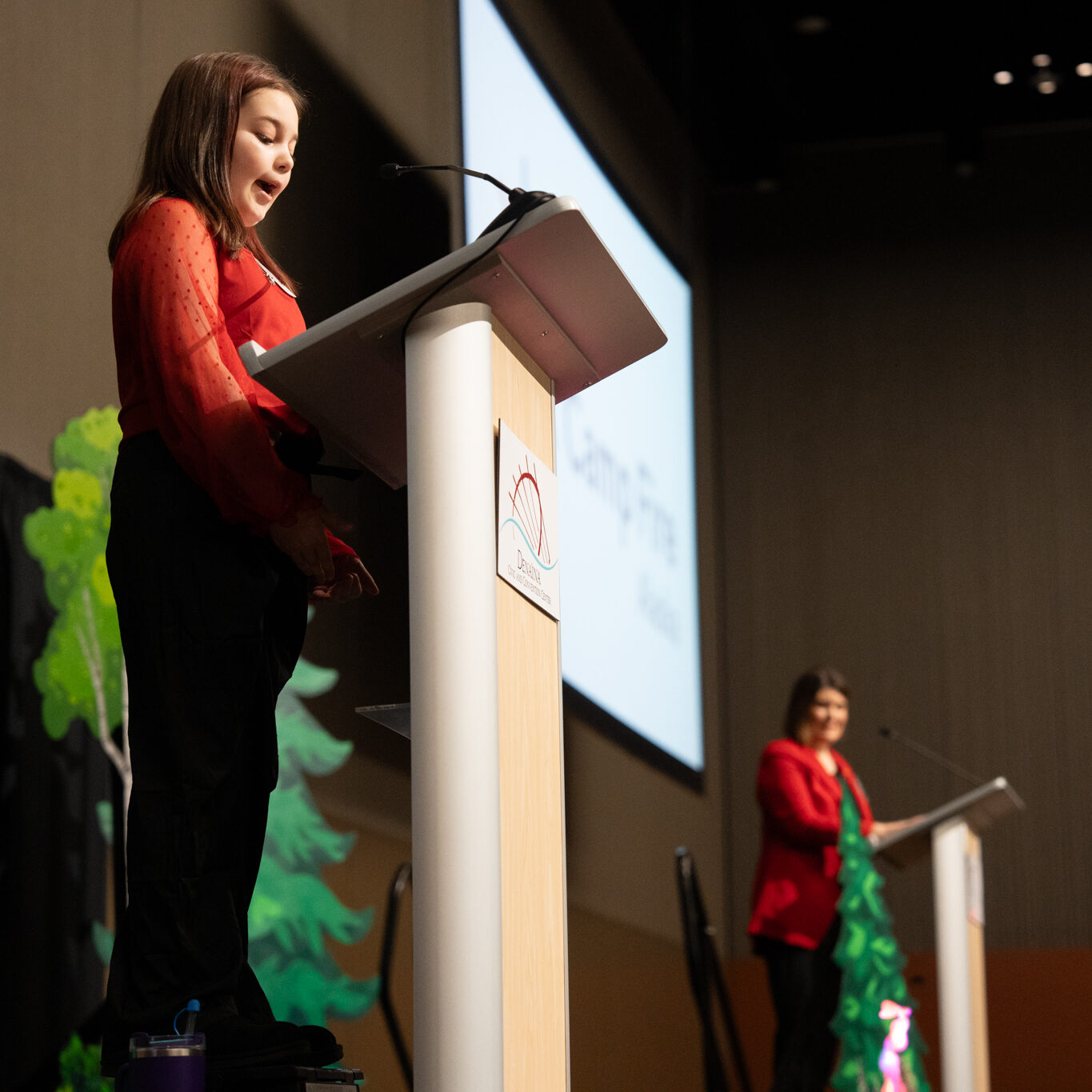 Emcees Katie Bates, Camp Fire Alaska Board Member, and sixth-grader Camp Fire kid Grace ask attendees for help supporting Camp Fire Alaska.