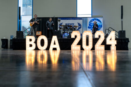 Band performs live music behind the BOA 2024 lit sign at Best of Alaska Showcase 2024