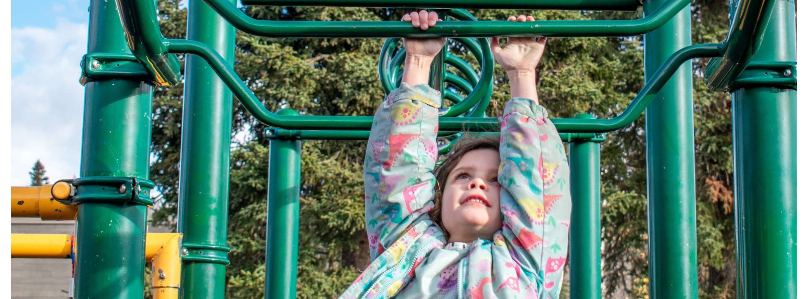 Camp Fire | Blog Image - Storytelling | Reaching for the Sky — Playground Edition - young girl reaches upwards towards the playground equipment with a large smile