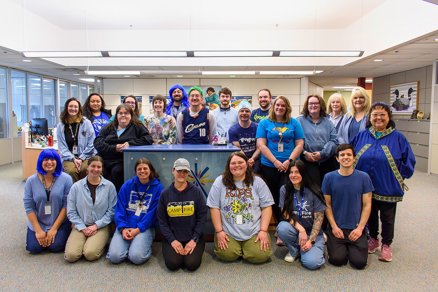 Group photo of 22 people dressed in blue, situated in the front of office of Camp Fire.